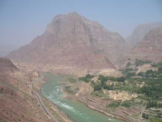 A view of Jishi Gorge, upstream from the landslide dam researchers say unleashed a great flood in China almost 4,000 years ago. Gray silt deposits are visible dozens of meters above the water. Wu Qinglong, CC BY-NC