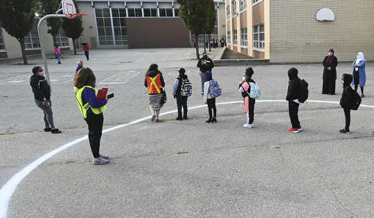 People wait in a physical distancing circle at the yard at Portage Trail Community School in Toronto on Sept. 15, 2020.  (four steps to teacher recovery from compassion fatigue and burnout)