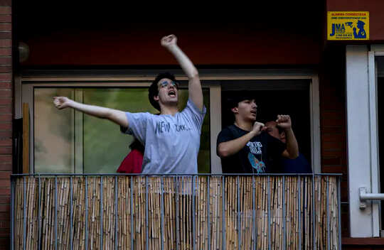 Two people on a balcony making music and dancing