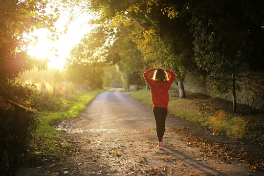 girl walking on a country road toward a bright light in the distance