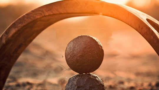 two balls balanced on top of each other under an arch