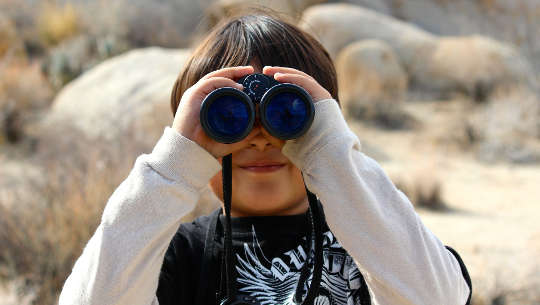 young boy looking through binoculars