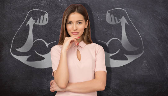 young woman standing in front of a chalkboard drawing of weightlifter muscles