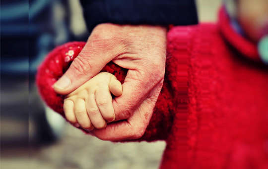 a young child walking and holding her father's hand