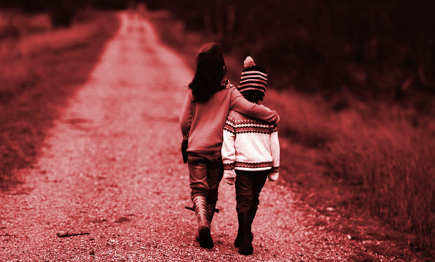 two children walking down a road with the taller one with her arm around the shoulders of the younger one