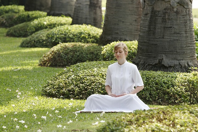 a woman in a white dress sitting in meditation