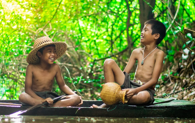 two boys sitting by the water and laughing joyfully