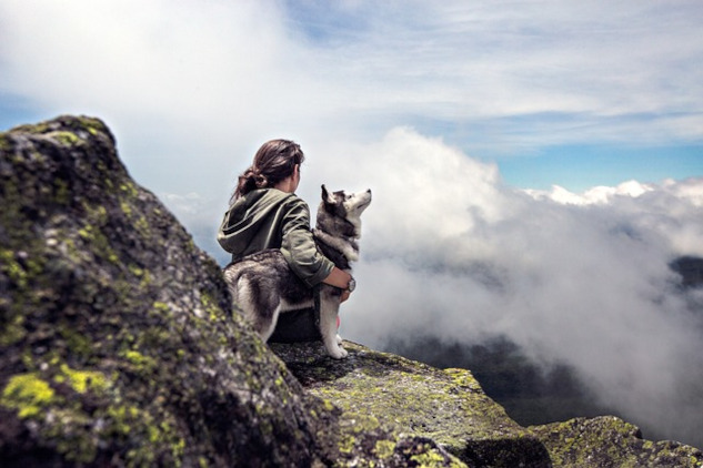 woman sitting outside with her arm around a husky dog