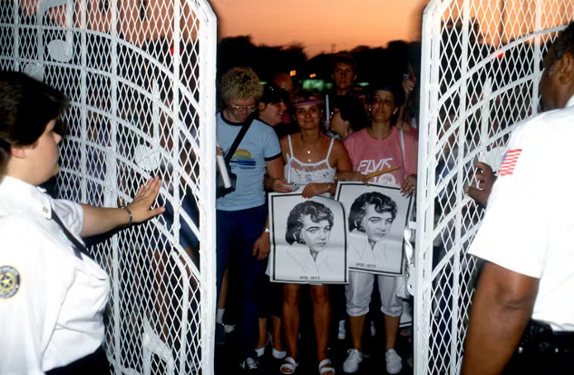 Fans at the gates of Graceland commemorating Elvis Presley, reflecting the cultural significance of his legacy.