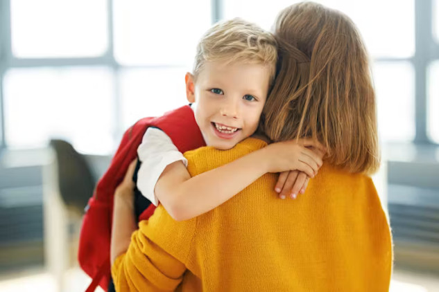 Child walking into school with backpack, smiling parent waving goodbye, representing a positive start to primary school.