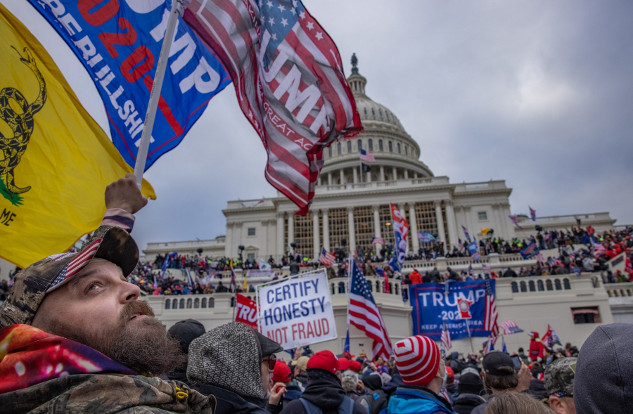 A crowd of protesters gathered outside the U.S. Capitol building, waving flags and holding signs supporting Donald Trump, during a political rally.