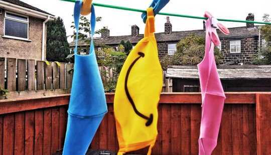 Three masks on a clothing line, one with a smiley face on it