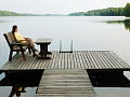 woman sitting on a bench on a platform dock surrounded by a very calm lake