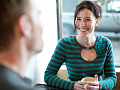 a smiling woman having a cup of coffee with someone