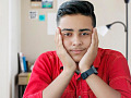 young man with his chin resting on his hands smiling peacefully