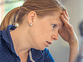 a woman in concentration resting her forehead on her hand