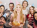 a group of friends smiling, one of them holding a birthday cake