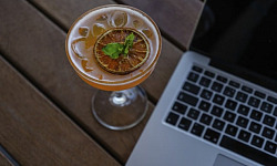 open laptop with a cocktail next to it