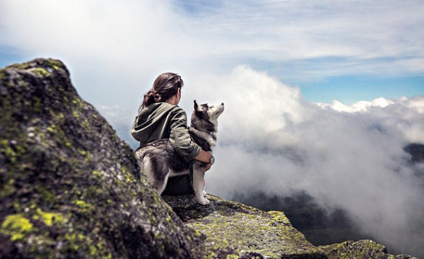 woman sitting outside with her arm around a husky dog