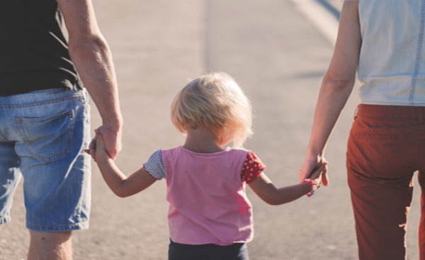 a child holding hands with her parents - one on each side