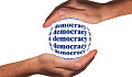 two hands protectively holding a globe named Democracy