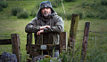 pensive man leaning on a gate