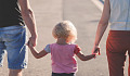 a child holding hands with her parents - one on each side