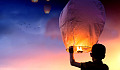 a young boy releasing lit-up balloons into the sky