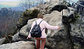 older woman wearing a backpack climbing a rocky path