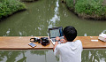 a young boy on a ship with his laptop open, and a camera and cell phone next to him.