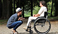 caring person squatting down in front of another in a wheelchair