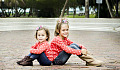 two smiling young sisters sitting back to back