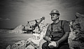 man sitting holding a big rock on a construction site