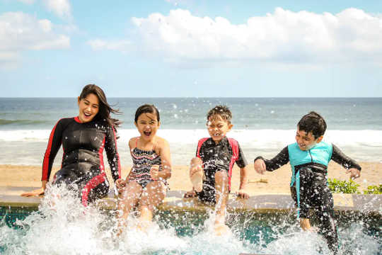 Family splashing in water by the seaside.