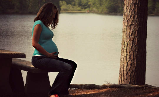 pregnant woman sitting with her hands on her belly