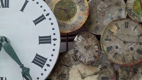 new clock in the foreground with several old clocks in the background