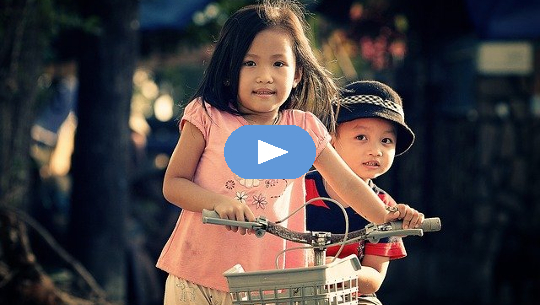 young girl on bike carrying her young brother behind her