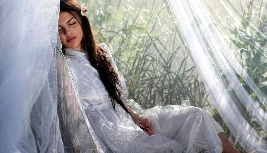 young woman sitting with eyes closed in a bay window