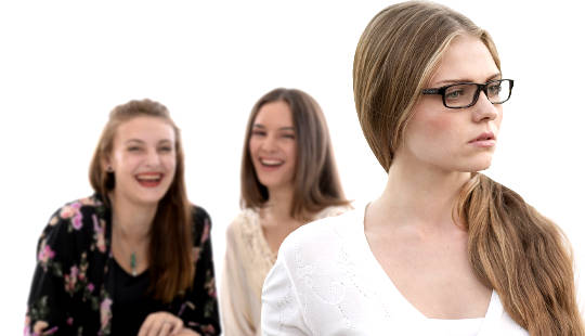 two young women laughing behind another woman's back