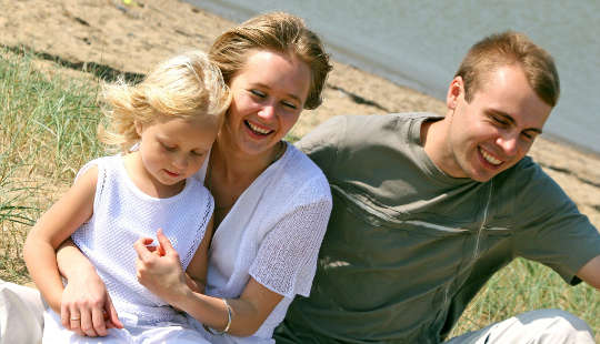 man. woman and child at the beach