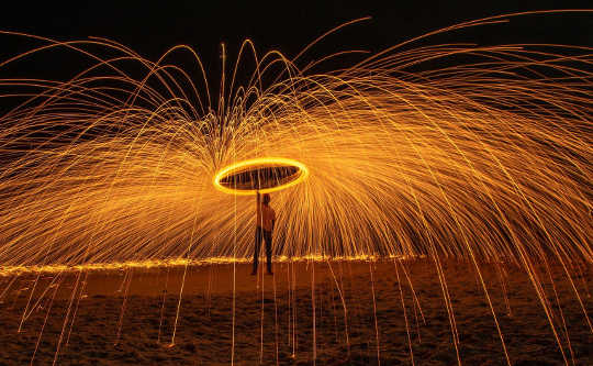 man holding an umbrella protecting him from sparks from a fire