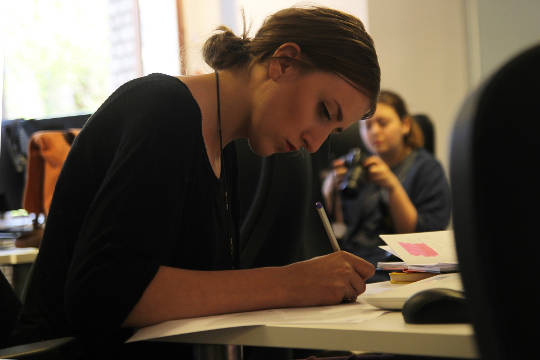 woman sitting at a desk working while someone in the background is not working