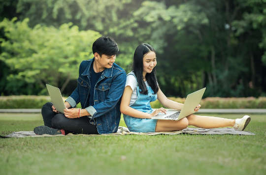 a young couple leaning against each other smiling broadly