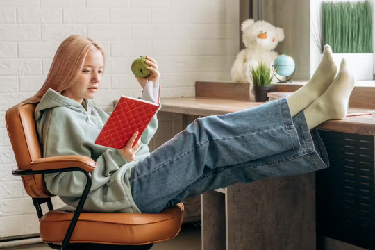 a young girl studying and eating an apple