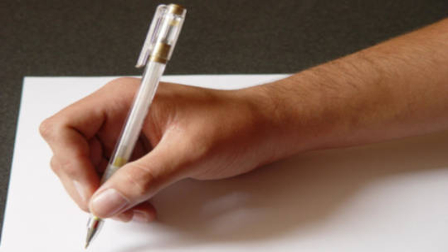 a person's hand holding a pen and writing