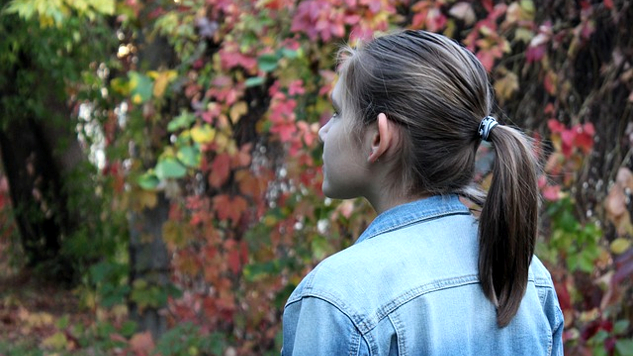 young woman looking out at some trees