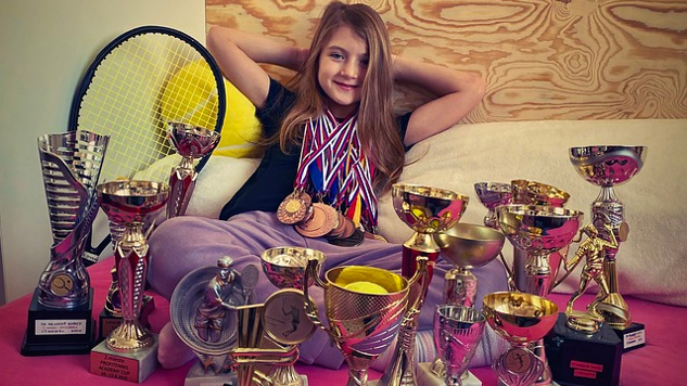 young girl with a lot of trophies in front of her