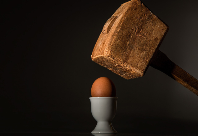 a hefty hammer being held over an egg