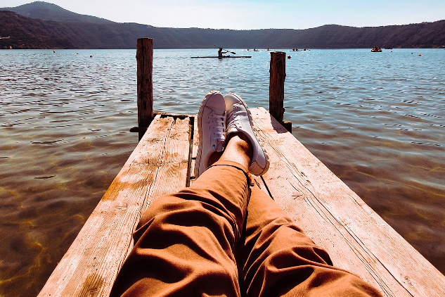 a man laying back on a dock, relaxing