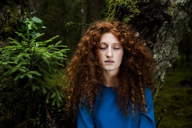 woman standing outside in nature with her eyes closed